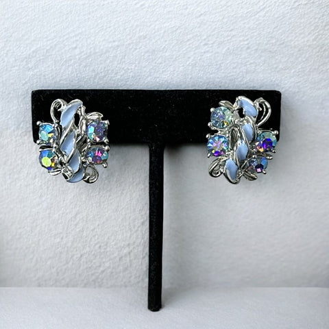 Vintage 1960s clip-on earrings featuring sparkling Aurora Borealis (AB) blue rhinestones in floral formations with delicate blue enamel leaf accents. Set in silver-tone metal, unworn and in excellent condition. Sustainable retro glam accessory, perfect for special occasions and vintage fashion lovers.