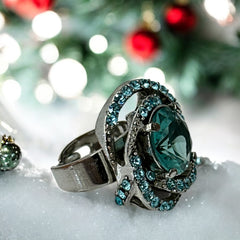 Adjustable silver-tone cocktail ring with a large round aqua rhinestone cabochon and open swirl design set with smaller teal rhinestones; vintage-inspired statement jewelry in very good condition.