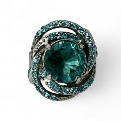 Adjustable silver-tone cocktail ring with a large round aqua rhinestone cabochon and open swirl design set with smaller teal rhinestones; vintage-inspired statement jewelry in very good condition.