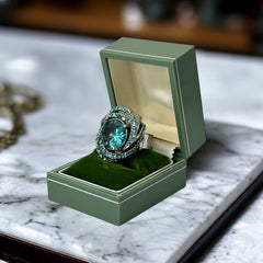 Adjustable silver-tone cocktail ring with a large round aqua rhinestone cabochon and open swirl design set with smaller teal rhinestones; vintage-inspired statement jewelry in very good condition.