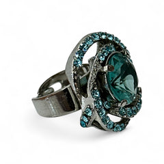 Adjustable silver-tone cocktail ring with a large round aqua rhinestone cabochon and open swirl design set with smaller teal rhinestones; vintage-inspired statement jewelry in very good condition.
