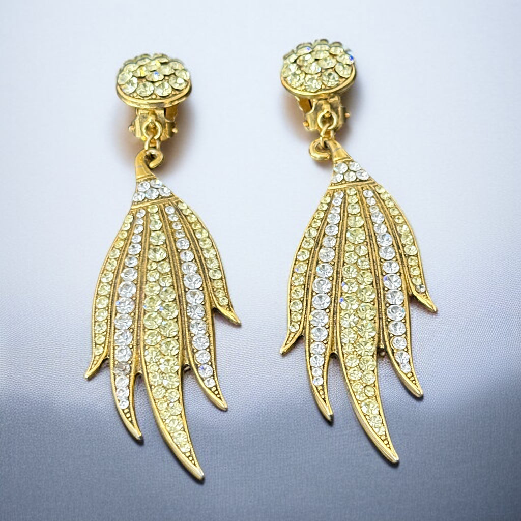 Vintage gold-tone clip-on earrings with jonquil and clear rhinestones in a feather-like Art Deco revival design; long dangle silhouette, 1970s style.