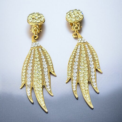 Vintage gold-tone clip-on earrings with jonquil and clear rhinestones in a feather-like Art Deco revival design; long dangle silhouette, 1970s style.