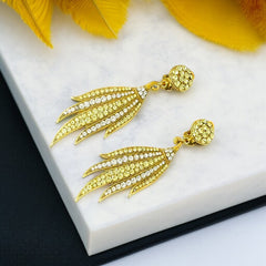 Vintage gold-tone clip-on earrings with jonquil and clear rhinestones in a feather-like Art Deco revival design; long dangle silhouette, 1970s style.