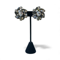Vintage 1950s silver-tone clip-on earrings with black diamond and clear rhinestones in a radiant pinwheel design; unsigned but crafted with rivet and swedge construction typical of Beau Jewels or Judy Lee, approx. 1¼" diameter, in very good vintage condition with secure clips and brilliant sparkle.