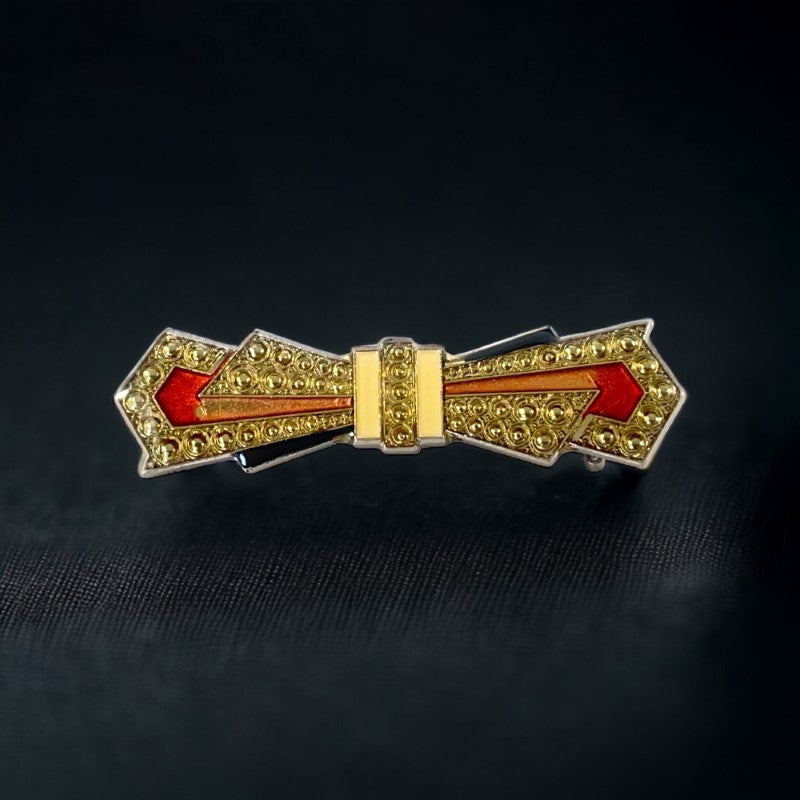 Vintage Art Deco style bow brooch with geometric enamel and resin design in black, gold, red, and white on silver tone base.