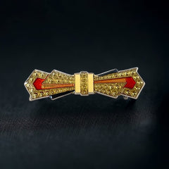 Vintage Art Deco style bow brooch with geometric enamel and resin design in black, gold, red, and white on silver tone base.