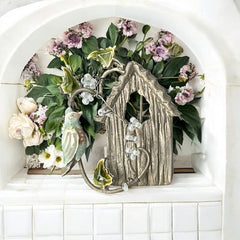 Vintage 1990s silver tone brooch featuring a light blue enamel bird perched on a wire branch with green enamel leaves and white seed bead flowers, set in front of a textured birdhouse; whimsical 3D design in very good vintage condition.