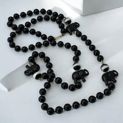 Vintage 1990s necklace featuring a symmetrical design with two elephant-shaped black beads, two black-and-white beads resembling banded agate, and a strand of 8mm black plastic beads in very good condition