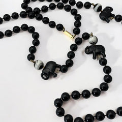 Vintage 1990s necklace featuring a symmetrical design with two elephant-shaped black beads, two black-and-white beads resembling banded agate, and a strand of 8mm black plastic beads in very good condition