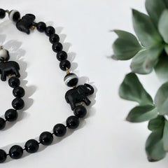 Vintage 1990s necklace featuring a symmetrical design with two elephant-shaped black beads, two black-and-white beads resembling banded agate, and a strand of 8mm black plastic beads in very good condition