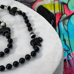 Vintage 1990s necklace featuring a symmetrical design with two elephant-shaped black beads, two black-and-white beads resembling banded agate, and a strand of 8mm black plastic beads in very good condition