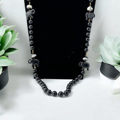 Vintage 1990s necklace featuring a symmetrical design with two elephant-shaped black beads, two black-and-white beads resembling banded agate, and a strand of 8mm black plastic beads in very good condition