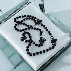 Vintage 1990s necklace featuring a symmetrical design with two elephant-shaped black beads, two black-and-white beads resembling banded agate, and a strand of 8mm black plastic beads in very good condition