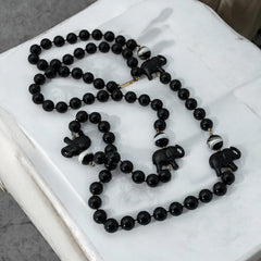 Vintage 1990s necklace featuring a symmetrical design with two elephant-shaped black beads, two black-and-white beads resembling banded agate, and a strand of 8mm black plastic beads in very good condition