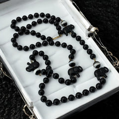 Vintage 1990s necklace featuring a symmetrical design with two elephant-shaped black beads, two black-and-white beads resembling banded agate, and a strand of 8mm black plastic beads in very good condition