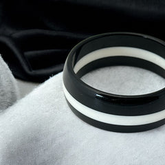 vintage black and white striped Lucite bangle bracelet with a sleek modern design inspired by 70s or 80s fashion. Featuring a white central ring framed by black rings on each side, this unsigned bracelet is in very good condition and makes a bold statement accessory.