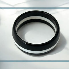 vintage black and white striped Lucite bangle bracelet with a sleek modern design inspired by 70s or 80s fashion. Featuring a white central ring framed by black rings on each side, this unsigned bracelet is in very good condition and makes a bold statement accessory.