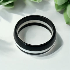 vintage black and white striped Lucite bangle bracelet with a sleek modern design inspired by 70s or 80s fashion. Featuring a white central ring framed by black rings on each side, this unsigned bracelet is in very good condition and makes a bold statement accessory.