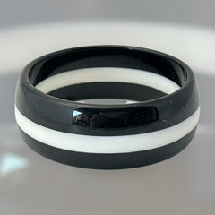 vintage black and white striped Lucite bangle bracelet with a sleek modern design inspired by 70s or 80s fashion. Featuring a white central ring framed by black rings on each side, this unsigned bracelet is in very good condition and makes a bold statement accessory.