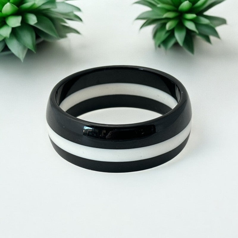 vintage black and white striped Lucite bangle bracelet with a sleek modern design inspired by 70s or 80s fashion. Featuring a white central ring framed by black rings on each side, this unsigned bracelet is in very good condition and makes a bold statement accessory.