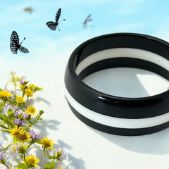 vintage black and white striped Lucite bangle bracelet with a sleek modern design inspired by 70s or 80s fashion. Featuring a white central ring framed by black rings on each side, this unsigned bracelet is in very good condition and makes a bold statement accessory.