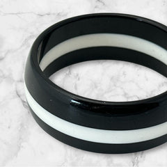 vintage black and white striped Lucite bangle bracelet with a sleek modern design inspired by 70s or 80s fashion. Featuring a white central ring framed by black rings on each side, this unsigned bracelet is in very good condition and makes a bold statement accessory.
