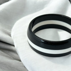 vintage black and white striped Lucite bangle bracelet with a sleek modern design inspired by 70s or 80s fashion. Featuring a white central ring framed by black rings on each side, this unsigned bracelet is in very good condition and makes a bold statement accessory.