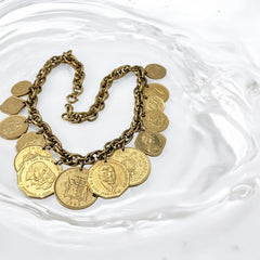 Vintage Franklin Mint Caribbean Coins necklace from the 1980s, featuring 14 uncirculated 24k gold-plated coins from Caribbean Islands on a textured chain.