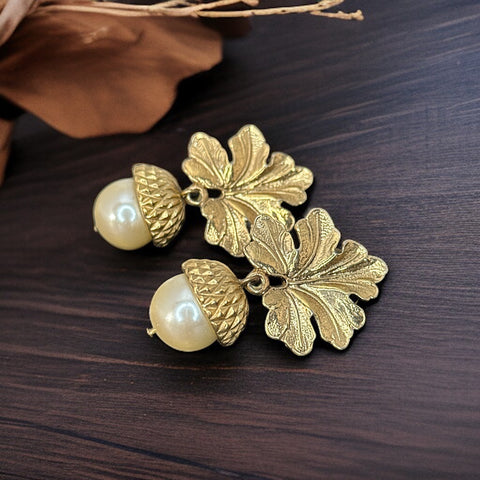 Vintage Carolee pierced earrings featuring gold-tone oak leaves and acorn caps with faux pearl drops. Signed Carolee © on the back, the earrings measure 1½ inches long by 1 inch wide and are in excellent vintage condition."