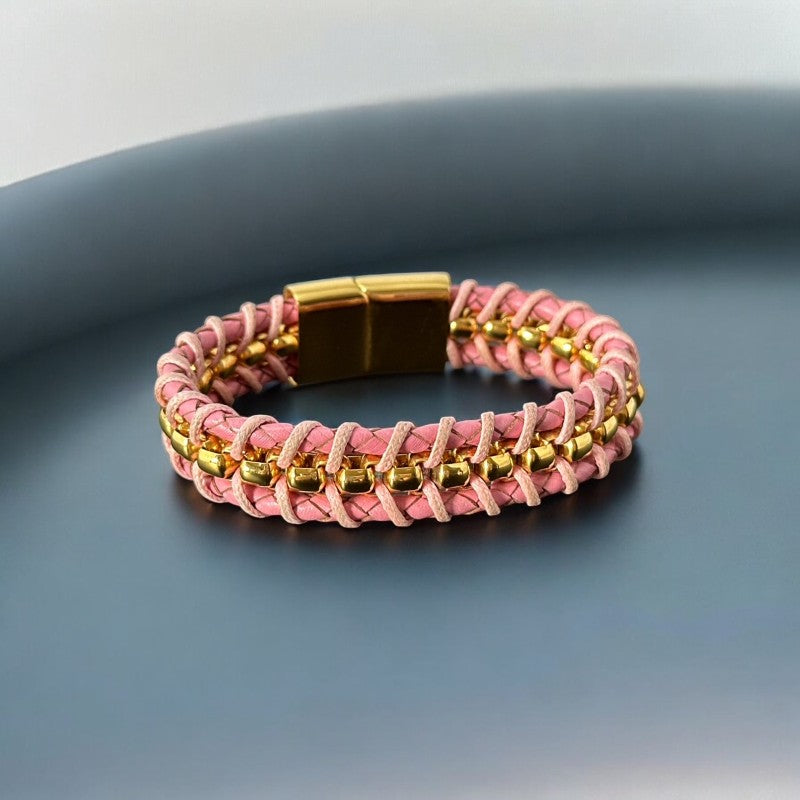 Elegant Daniel Steiger Melrose bracelet featuring braided pink leather on each side of yellow gold-plated center links, finished with a gold-plated magnetic slide clasp, photographed against a neutral backdrop.