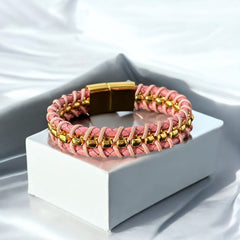 Elegant Daniel Steiger Melrose bracelet featuring braided pink leather on each side of yellow gold-plated center links, finished with a gold-plated magnetic slide clasp, photographed against a neutral backdrop.