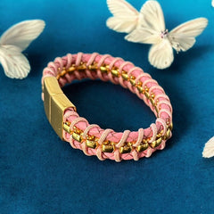 Elegant Daniel Steiger Melrose bracelet featuring braided pink leather on each side of yellow gold-plated center links, finished with a gold-plated magnetic slide clasp, photographed against a neutral backdrop.