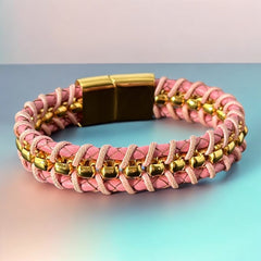 Elegant Daniel Steiger Melrose bracelet featuring braided pink leather on each side of yellow gold-plated center links, finished with a gold-plated magnetic slide clasp, photographed against a neutral backdrop.