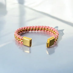 Elegant Daniel Steiger Melrose bracelet featuring braided pink leather on each side of yellow gold-plated center links, finished with a gold-plated magnetic slide clasp, photographed against a neutral backdrop.