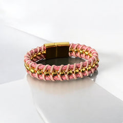 Elegant Daniel Steiger Melrose bracelet featuring braided pink leather on each side of yellow gold-plated center links, finished with a gold-plated magnetic slide clasp, photographed against a neutral backdrop.