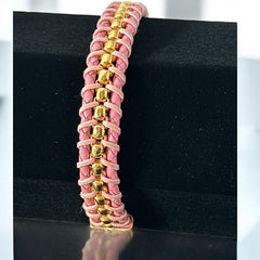 Elegant Daniel Steiger Melrose bracelet featuring braided pink leather on each side of yellow gold-plated center links, finished with a gold-plated magnetic slide clasp, photographed against a neutral backdrop.