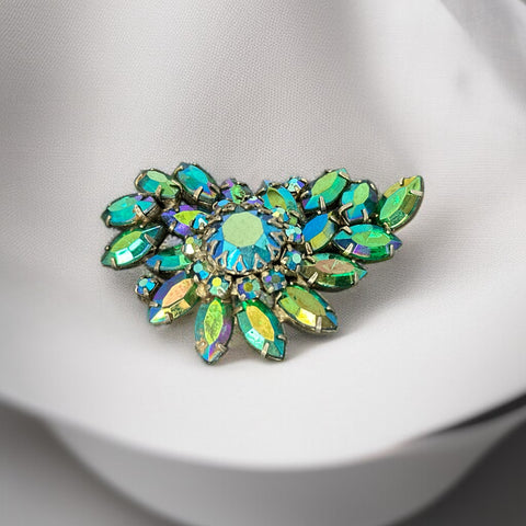 Vintage 1950s brooch featuring layered AB emerald rhinestones in marquise and chaton cuts, set in silver tone metal with a central dog tooth prong setting; photographed to highlight sparkle, craftsmanship, and mid-century design.