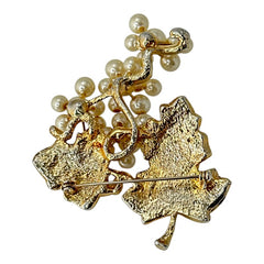Elegant vintage 1980s brooch featuring a gold-tone grape vine design with round faux pearls forming the grape cluster. The leaves are adorned with sparkling clear pave rhinestones, adding a luxurious touch. Unsigned and in very good vintage condition, this brooch is a timeless statement piece.
