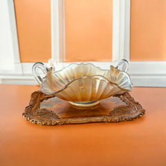 Vintage Fenton marigold carnival glass dish with stippled rays pattern, featuring a ruffled scalloped edge and clear double handles; warm amber iridescence with visible air bubbles