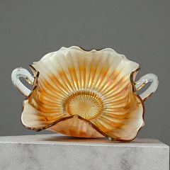 Vintage Fenton marigold carnival glass dish with stippled rays pattern, featuring a ruffled scalloped edge and clear double handles; warm amber iridescence with visible air bubbles