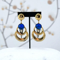 Vintage French modernist clip-on earrings with faceted blue round cabochons, layered gold and silver-tone metal crescents, and long sculptural dangles; shown from multiple angles to highlight texture, asymmetry, and mixed-metal design.
