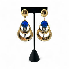 Vintage French modernist clip-on earrings with faceted blue round cabochons, layered gold and silver-tone metal crescents, and long sculptural dangles; shown from multiple angles to highlight texture, asymmetry, and mixed-metal design.