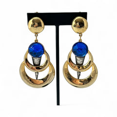 Vintage French modernist clip-on earrings with faceted blue round cabochons, layered gold and silver-tone metal crescents, and long sculptural dangles; shown from multiple angles to highlight texture, asymmetry, and mixed-metal design.