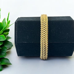 Vintage French gold-plated curb mesh bracelet from the 1960s/70s, featuring three soldered curb chains with a textured mesh design, a safety catch clasp with a safety chain, and intriguing marks (5M and an unclear jeweler's signature). Measures 8 inches long and showcases light vintage wear.
