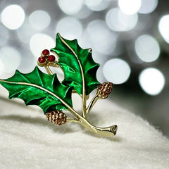 Vintage Gerry’s holly brooch with red enamel berries and metallic green enamel leaves on a gold-tone stem; signed Gerry’s on the back, 1980s holiday jewelry in very good condition with minor enamel wear.