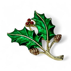 Vintage Gerry’s holly brooch with red enamel berries and metallic green enamel leaves on a gold-tone stem; signed Gerry’s on the back, 1980s holiday jewelry in very good condition with minor enamel wear.