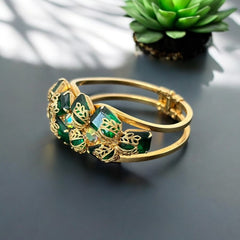 Vintage Juliana clamper bracelet from the 1950s, featuring 10 emerald-shaped rhinestones with filigree leaves, three AB light green rhinestones, and a gold-tone finish. A glamorous statement piece in excellent condition.