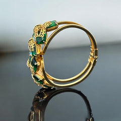 Vintage Juliana clamper bracelet from the 1950s, featuring 10 emerald-shaped rhinestones with filigree leaves, three AB light green rhinestones, and a gold-tone finish. A glamorous statement piece in excellent condition.