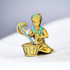 Vintage Hattie Carnegie snake charmer brooch with turquoise cabochons and blue rhinestones, gold tone metal, signed with copyright mark, 1960s figural costume jewelry.